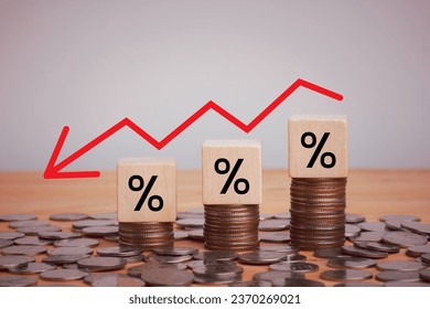 Percentage sign on wooden cubes with Stack of coin bar chart and red graph trending downwards on white background. Economy recession crisis, inflation, stagflation, business and financial loss concept