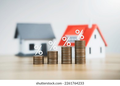 the percentage symbol for increasing interest rates on stacks of coins and the model house. Interest rates increase, home loan, mortgage, house tax. investment and asset management concept