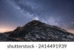Perched atop a lonely peak, a group of adventurers become silhouettes against the sprawling tapestry of the Milky Way, in a moment that feels both vast and intimate.
