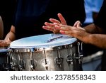 A percussion instrument from a samba school being played by male hands.