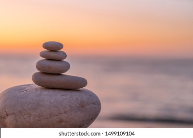 Perfect balance of stack of pebbles at seaside towards sunset. Concept of balance, harmony and meditation. Helping or supporting someone for growing or going higher up. - Powered by Shutterstock