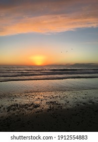 Perfect Beach Sunset In Southern California. Calm Waves Can Be Seen With Birds Flying Overhead. 