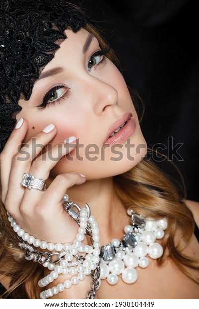 Perfect beauty and\
jewelry concept. Portrait of beautiful female model wearing ring,\
necklace and wristband on black background. Young blond woman shows\
glamorous finery.