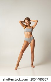 Perfect body shape. Full-length portrait of cute beautiful caucasian woman with slim fit figure in gray inner wear posing on grey studio background. Concept of female body, health, sport, spa, ad