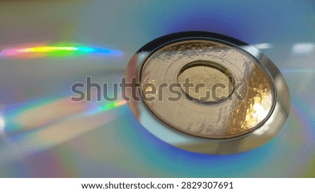 Perfect central ring of a compact disc casting subtle rainbow colors onto a grey silver floor. industrial minimalism, musical storage, tech object.