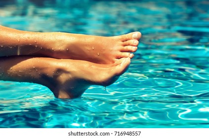 Perfect clean female feet above water  . Beautiful and elegant groomed girl's hand touching  her foot . Spa ,scrub and foot care .