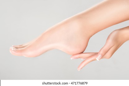 Perfect clean female feet . Beautiful and elegant groomed girl's hand touching  her foot . Spa ,scrub and foot care . - Shutterstock ID 471776879