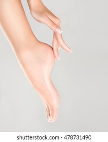 Perfect clean female feet . Beautiful and elegant groomed girl's hand touching  her foot . Spa ,scrub and foot care . - Shutterstock ID 478731490