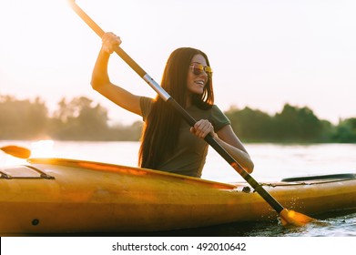 Perfect day for kayaking. Beautiful young smiling woman paddling while sitting in kayak  - Powered by Shutterstock