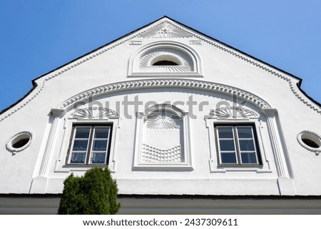 Perfect example of a sensitive renovation of an old house, with keeping all the traditional historical details. White facade. Brigh blue sky. Dlouhomilov, Moravia, Czech republic.