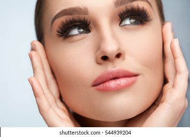 Perfect Face Makeup. Closeup Portrait Of Beautiful Sexy Woman With Professional Makeup Touching Her Smooth Soft Healthy Facial Skin. Glamorous Female Model With Long Black Eyelashes. High Resolution