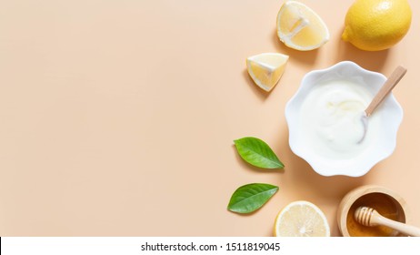 Perfect homemade natural face mask ingredients for bright and healthy skin. Top view of yogurt, lemon and honey on orange background. Beauty herbal skincare product concept. Flat lay. Copy space.