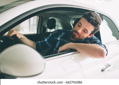 Perfect Lines. The Young Dark-haired Bearded Man Examining Car At The Dealership And Making His Choice. Horizontal Portrait Of A Young Guy At The Car. He Is Thinking If He Should Buy It