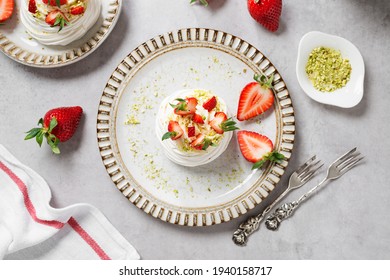 Perfect mini Pavlova cake with whipped mascarpone cream and fresh strawberry slices, sprinkled with crushed pistachios. top view