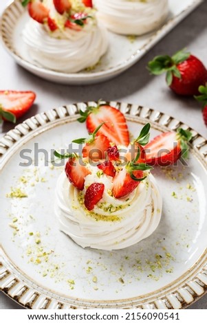Perfect mini Pavlova cake with whipped mascarpone cream and fresh strawberry slices, sprinkled with crushed pistachios. 