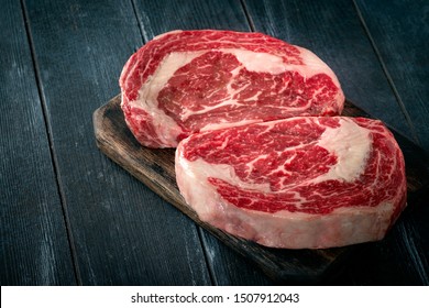 Perfect raw rib eye beef steak on black wooden background, close-up