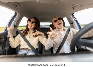 Perfect road trip. Excited spouses in sunglasses driving car, enjoying music and singing favorite song, windshield view - Powered by Shutterstock