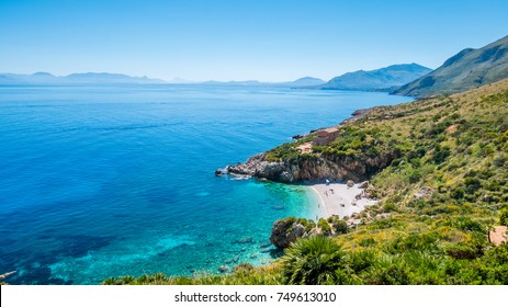 The perfect secret beach: white pebbles beach and turquoise sea, surrounded by luxuriant vegetation of the natural reserve “Riserva dello Zingaro”, San Vito Lo Capo, Sicily, Mediterranean Sea, Italy. - Powered by Shutterstock