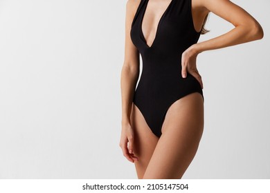 Perfect shape of belly, hips. Adorable body of young slim woman in black swimsuit isolated on gray background. Natural beauty concept. Wellness, weight loss, treatment, health care, fitness concept.