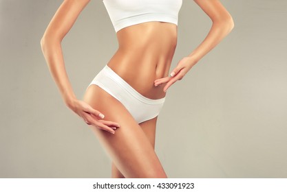  Perfect slim toned young body of the girl . An example of sports , fitness or plastic surgery and aesthetic cosmetology.



