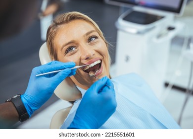 Perfect smile! Part of dentist examining his beautiful patient in dentist office. European young woman smiling while looking at mirror in dental clinic - Powered by Shutterstock