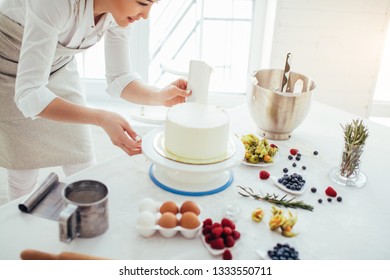 Perfect Smooth. Chef Holding A Bench Scraper Vertically Agains The Cake. Close Up Side View Cropped Photo