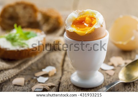 Perfect soft boiled egg and open bread sandwich with butter and dill on a table. Traditional food for healthy breakfast.
