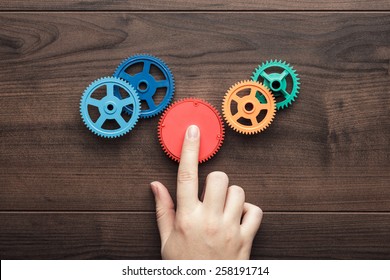 perfect solution concept. colorful gears and hand on the brown wooden background