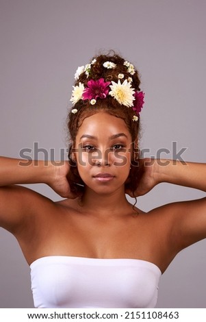 Perfect for the spring goddess in you. Studio shot of a beautiful young woman with flowers in her hair against a gray background.