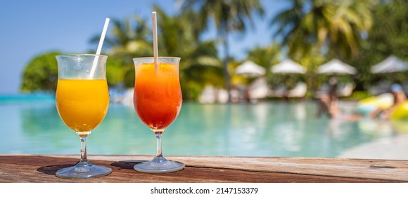 Perfect summer beach resort, poolside with two colorful cocktails. Tropical swimming pool, exotic summer vacation. Chairs, umbrella blurred palm tree leaves, amazing landscape. Freedom relax holiday