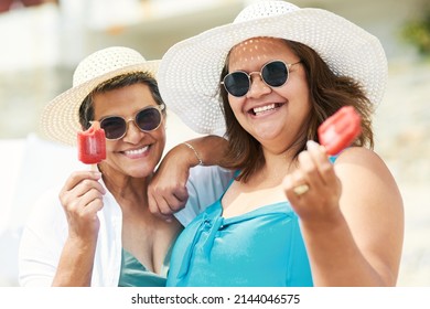 The Perfect Summer Cool Down. Shot Of Two Mature Friends Standing Together And Enjoying Ice Cream While Bonding On The Beach During The Day.