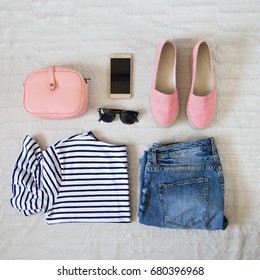 Perfect Summer Outfit Accessories. Flat Lay Of A Trendy Woman Fashion Outfit. Denim Jeans, Striped Shirt, Pink Espadrilles Shoes, Pink Bag, Sunglasses And A Elegant Smartphone. Top View.

