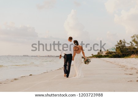 Perfect Sunset Destination Beach Wedding with Beautiful Bride and Groom Walking Down the Coastline