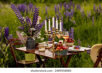 Perfect surprise date for loving couple, private wedding, romantic marriage proposal. Summer, sunset, golden hour. Appetisers. Beautiful elegant outdoor arrangement in meadow with purple blue lupins - Powered by Shutterstock