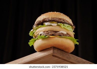 perfect tasty big double burger on wooden table on brown background, bottom view
