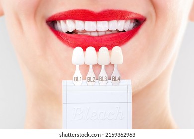Perfect white smile red lips with shade guide bleach color tooth dental whitening, bleaching, quality control and color check at artificial dentition, crown veneer smile, dental care and stomatology