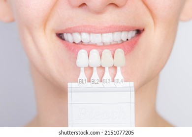 Perfect white smile with shade guide bleach color tooth dental whitening, bleaching, quality control and color check at artificial dentition, female crown veneer smile, dental care and stomatology