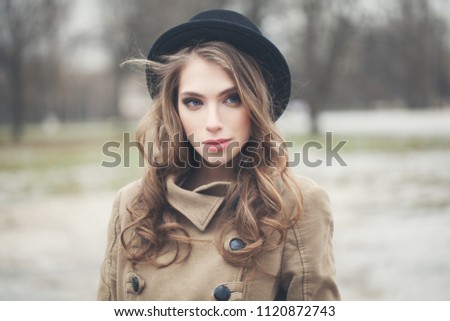 Perfect young woman in black hat outdoors in park. Perfect female face closeup