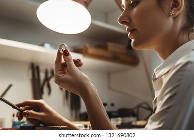 Perfection. Close up of young female jeweler looking and inspecting a ring. - Powered by Shutterstock