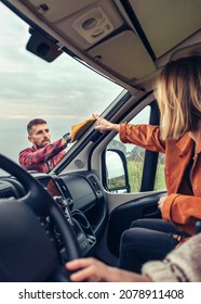 Perfectionist Man Cleaning Motorhome Windshield With Cloth While Woman Pointing Stain