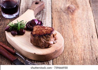 Perfectly Cooked Filet Mignon Served On Wooden Cutting Board With Roasted Red Onion And Rosemary