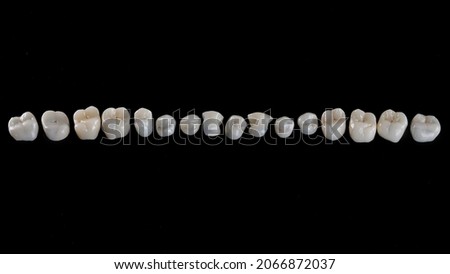 Perfectly laid out dental crowns with morphology on black glass, top view