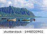 A Perfectly Still Kaneohe Bay Creates a Perfect Reflection of the Mountains and Old Boats in the Water.