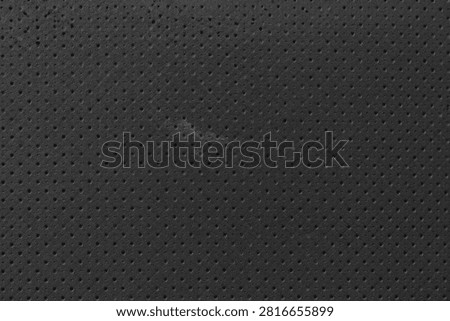 Perforated Black Leather Texture. Dark charcoal patterned vinyl background showcasing a scuffed spot symbolizing resilience and modern industrial utility