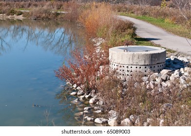 A Perforated Concrete Pipe Forms Part Of A Stormwater Management System In A Suburban Pond.