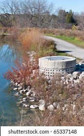 A Perforated Concrete Pipe Forms Part Of A Stormwater Management System In A Suburban Pond.