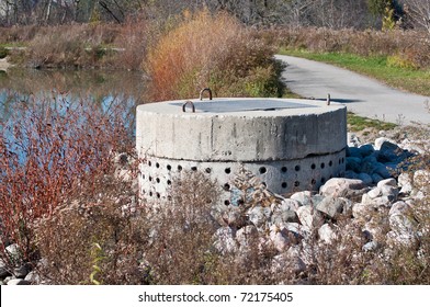 A Perforated Concrete Pipe Forms Part Of A Stormwater Management System In A Suburban Pond.