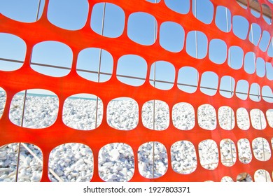 Perforated safety orange plastic grid to delimit construction site areas.
