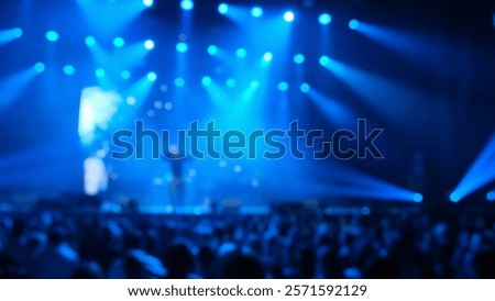 Performance of the boy group on stage, blue and white lights. A merry people crowd cheers, dancing and having fun on the dancefloor to the music of their favorite band. Night club party. Blurred shot