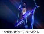 Performance by a circus acrobat artist. Girls perform aerial acrobatic elements on fabric.